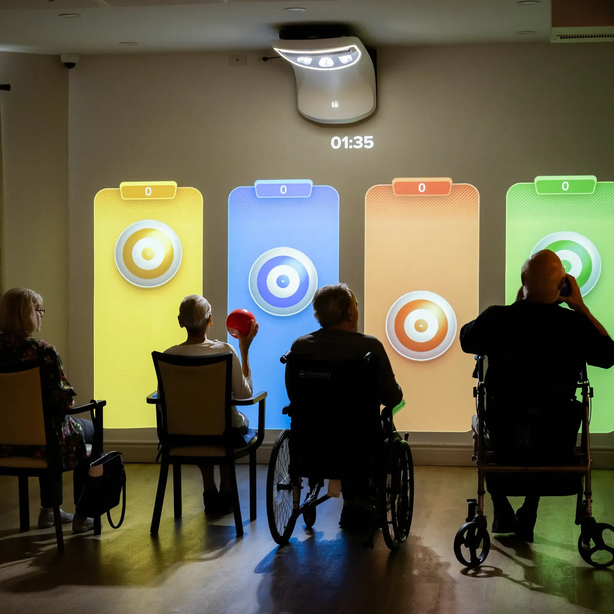 Seniors seated and in wheelchairs playing a target game projected on the wall with Höp